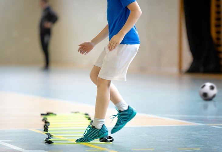 Young footballer using an agility ladder