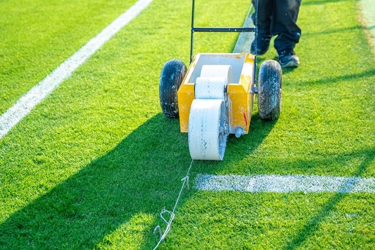 A groundsperson marks out the lines on a football pitch