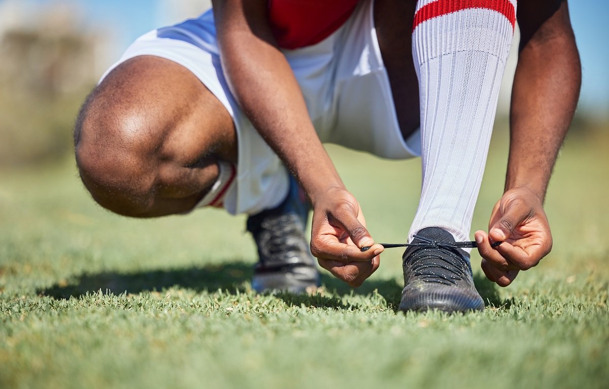 Football player lacing up boots