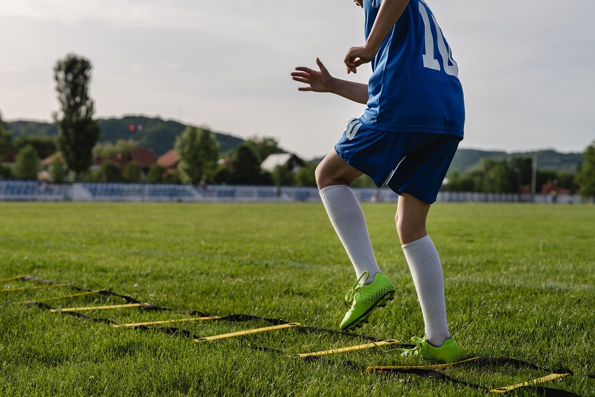 Footballer training with speed ladder