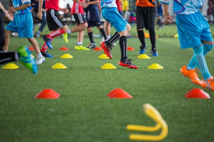 Young players running in between football cones