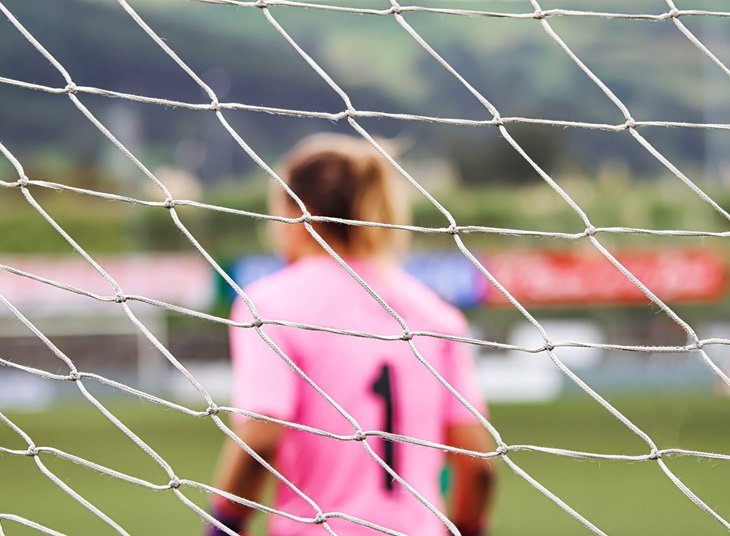 A woman goalkeeper sets her position